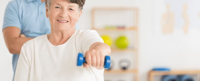 Older adult woman lifting a hand weight in physical therapy.