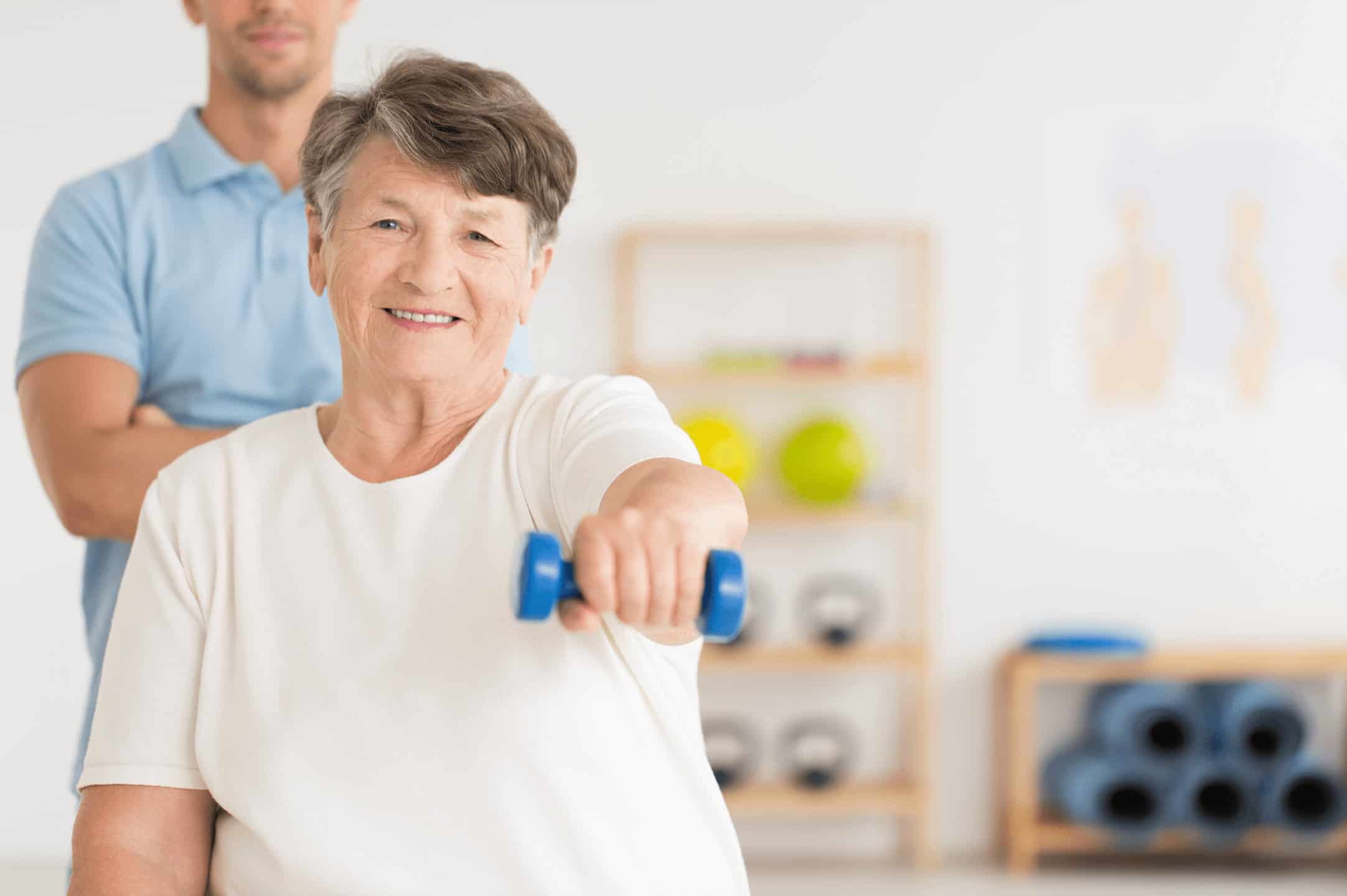 Older adult woman lifting a hand weight in physical therapy.