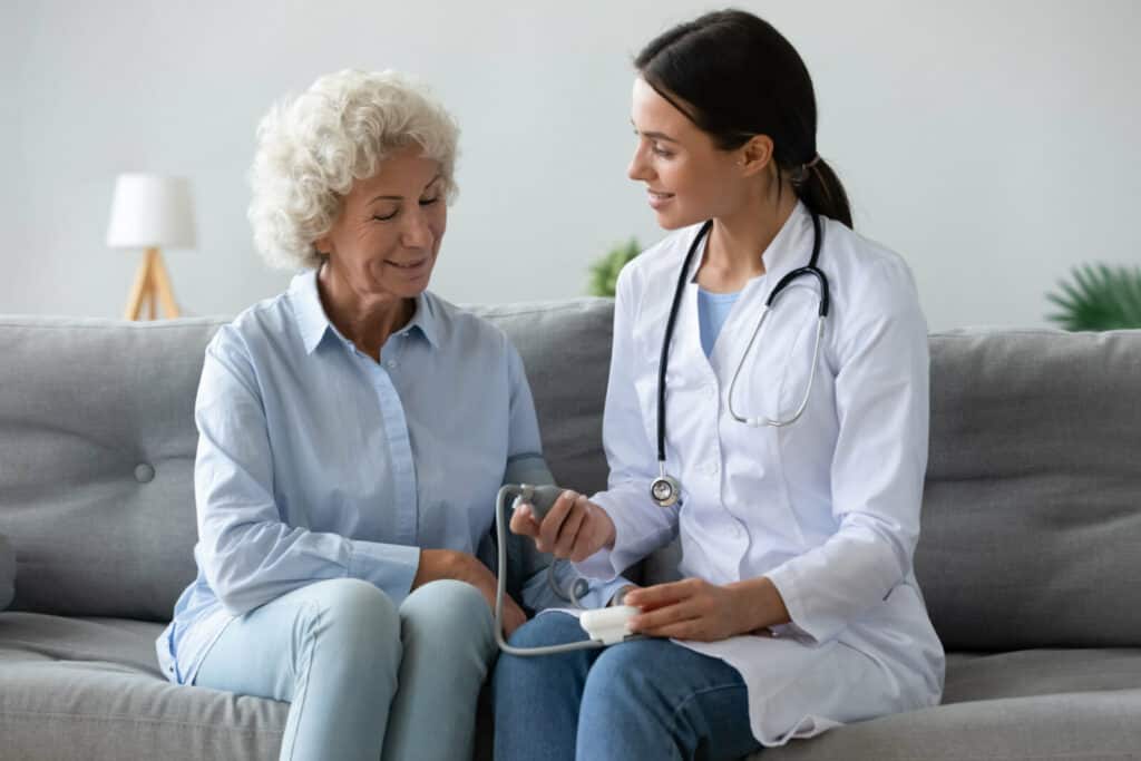 a mature woman getting her blood pressure checked, two women sitting on a couch